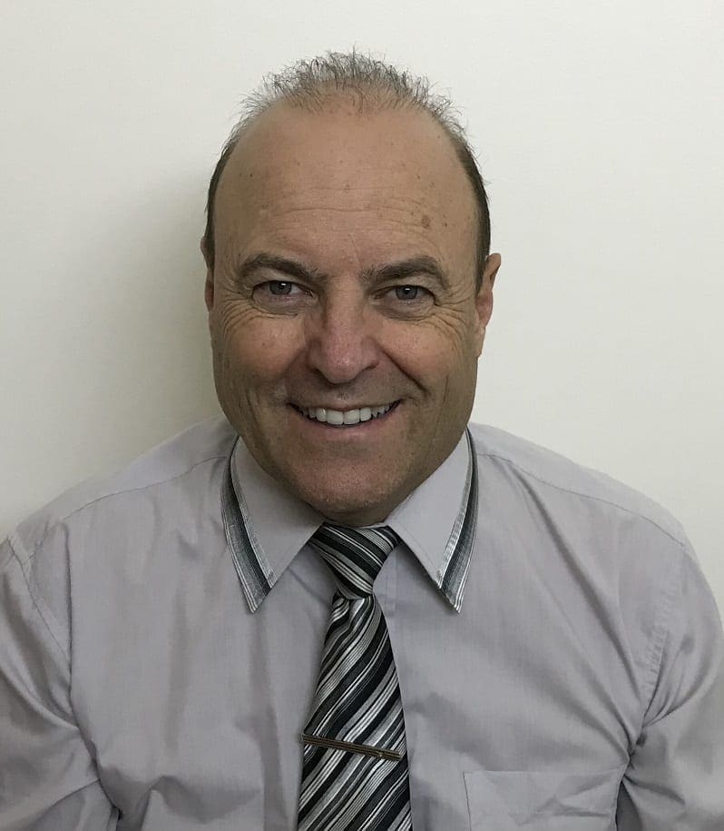 A man with a tie and shirt smiling for the camera.