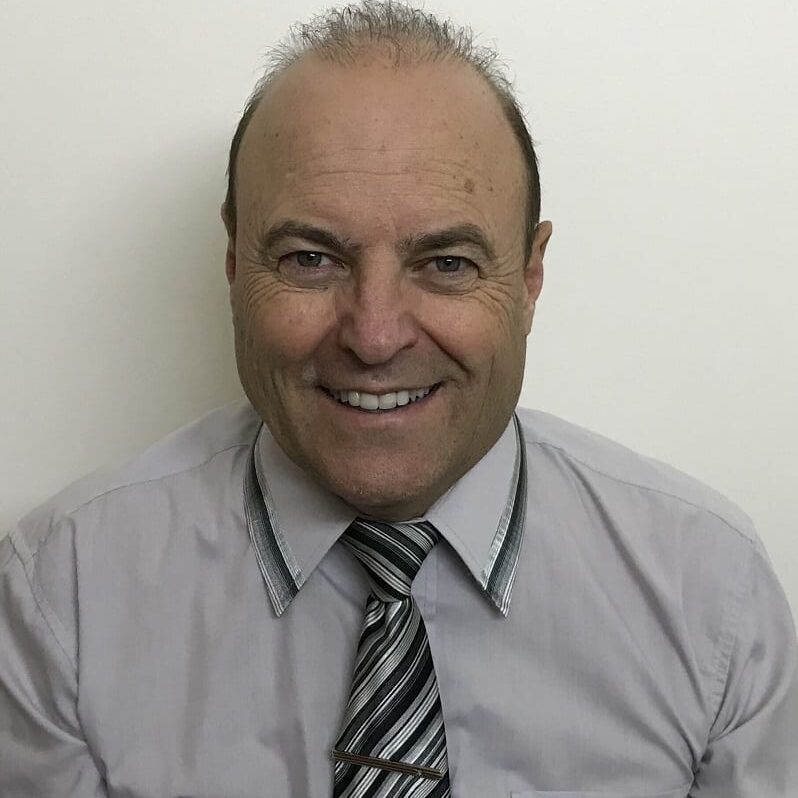 A man with a tie and shirt smiling for the camera.