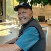 A man wearing a hat and vest smiling for the camera.