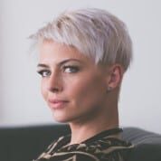 A woman with short hair sitting in front of a wall.